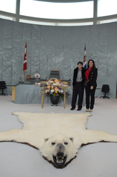 Augustin Lacoursière-Barthe (Youth Parliamentarian MLA Yellowknife North) standing beside the Mace. Polar bear rug in foreground.