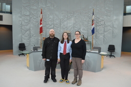 Michael Ball, Manager, Journals, Kagan Ball (Youth Parliamentarian MLA Yellowknife South), and Dana Ball infront of Mace and Speaker's Chair.